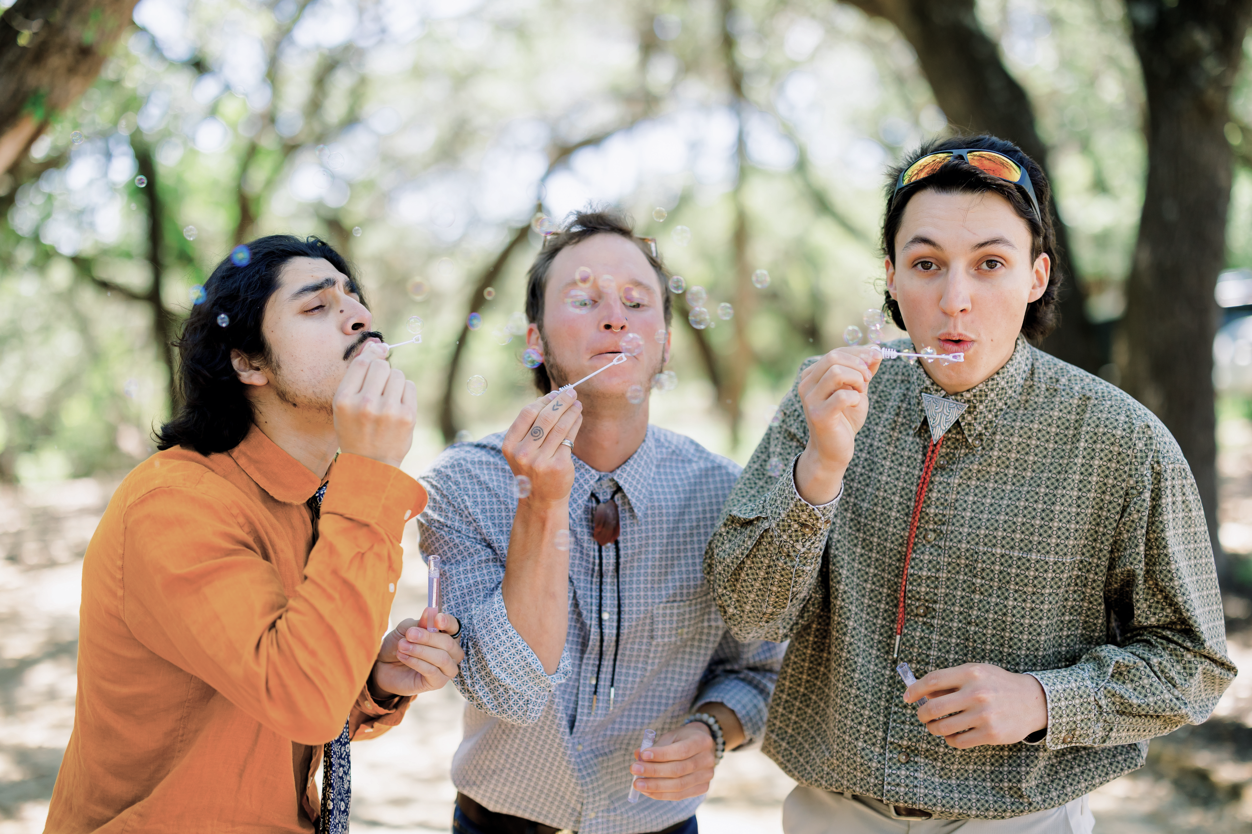Groomsmen blowing bubbles under the oaks