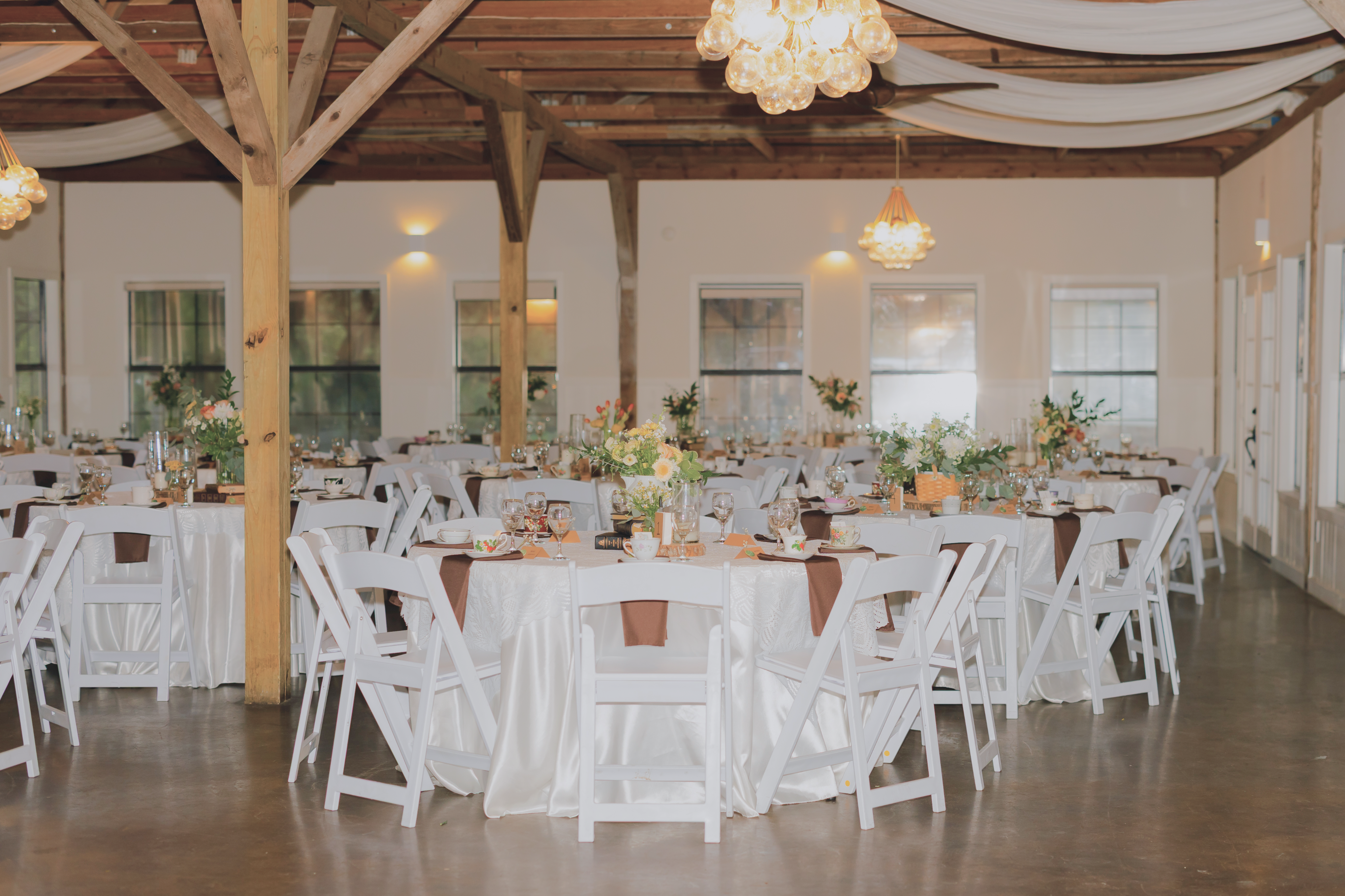 Round tables in the hall set with teacups and brown napkins