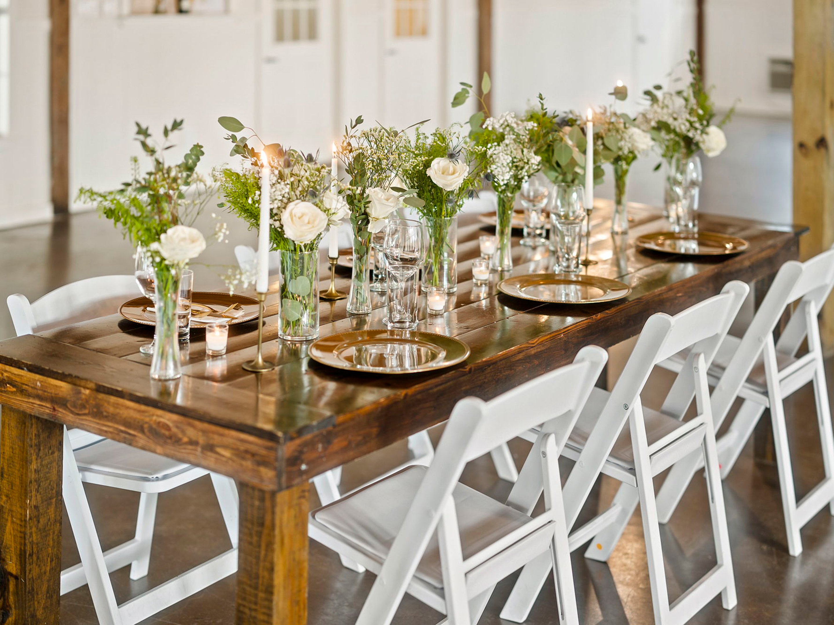 Farm table set with roses, greenery and gold chargers